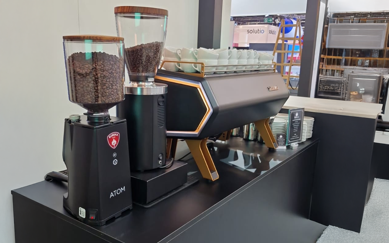 Ein hell gestalteter Messestand mit futuristisch anmutender Maschine | Kaffee-Catering - Messe